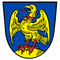 Ein Adler mit roten Füßen steht auf einem gelben Kreis auf einem blauen Schild. Er hat einen roten Kragen um den Hals und sein Schnabel ist geöffnet.