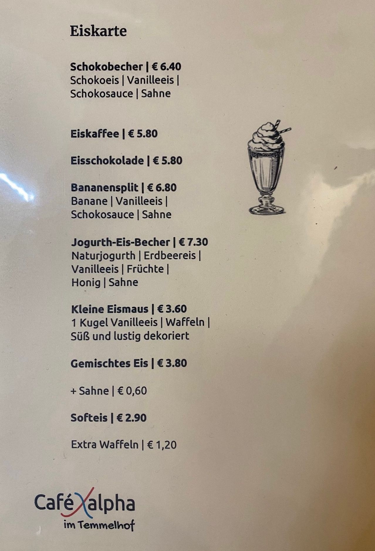 Ein Menü zeigt verschiedene Eiscreme-Optionen. Eiskaffee kostet 5,80 €, Eisschokolade kostet 5,80 € und ein Bananensplit kostet 6,80 €. Andere Artikel umfassen Jogurt-Eis-Becher für 7,30 €, Kleine Eismaus für 3,60 € und Gemischtes Eis für 3,80 €. Softeis kostet 2,90 € und extra Waffeln kosten 1,20 €.