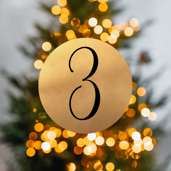 Ein goldener Kreis mit der Nummer 3 in schwarzer Schrift auf einem beleuchteten Weihnachtsbaum.