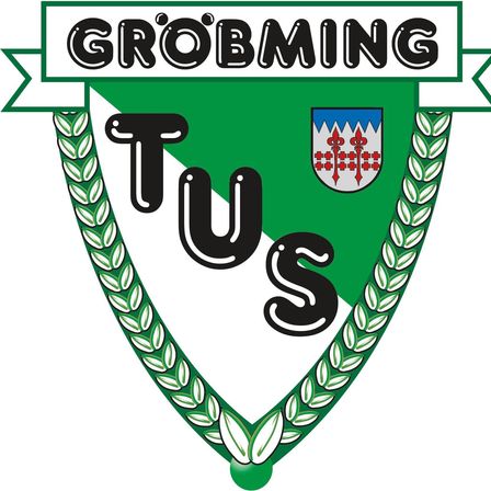 Ein grüner Schild mit dem Wort Groebming oben und den Buchstaben TUS in Schwarz darunter. Es zeigt ein Wappen mit einem roten Kreuz und vier roten Fleur-de-Lis auf weißem Hintergrund.