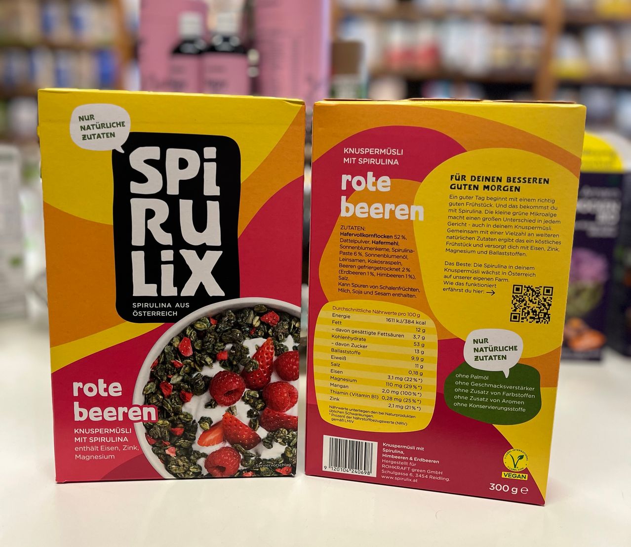 Zwei Schachteln SpiruLix rote Beeren sind abgebildet. Die Vorderseite der Schachtel zeigt eine Schüssel mit Spirulina und Erdbeeren. Die Rückseite der Schachtel hebt Nährwertinformationen, Zutaten und gesundheitliche Vorteile hervor.