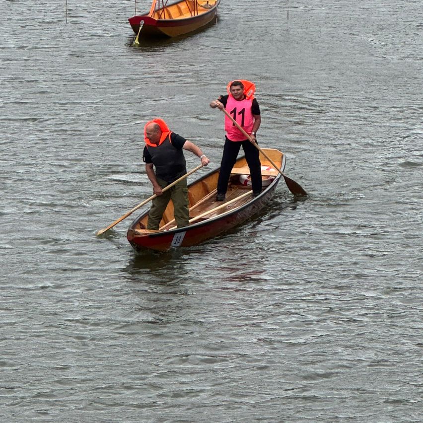 Zwei Männer in Rettungswesten rudern ein rotes Boot mit der Nummer 11. Ein weiteres Boot ist dahinter.