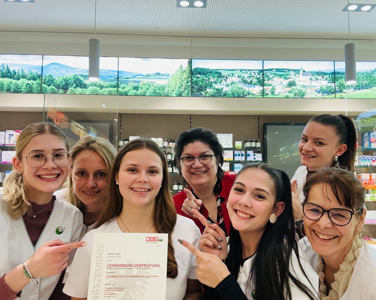 Eine Gruppe von Menschen, wahrscheinlich Studenten, posiert für ein Foto. Eine Frau hält ein Zertifikat. Sie tragen alle weiße Laborkittel.