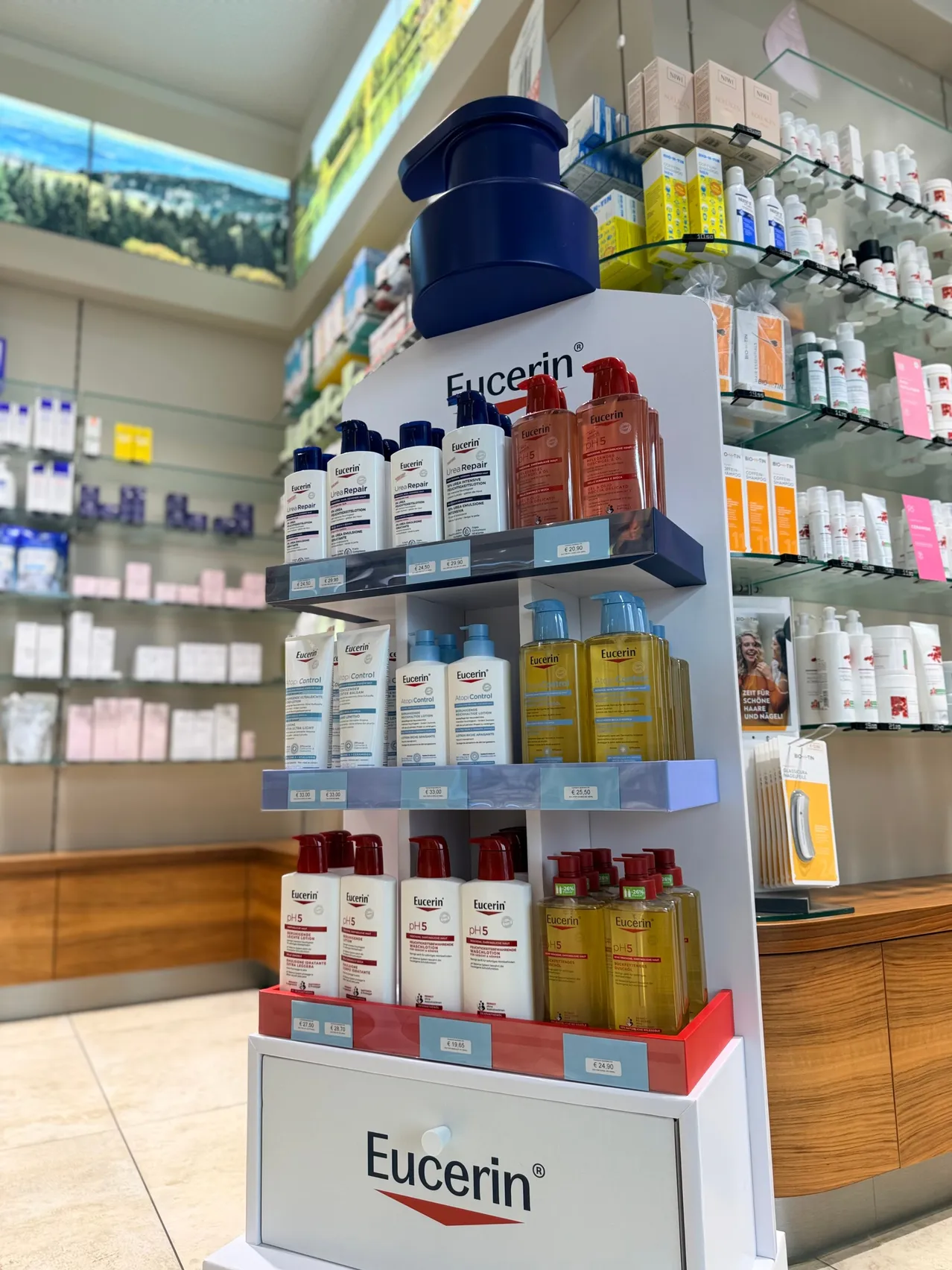 Ein Apothekenregal zeigt verschiedene Eucerin-Hautpflegeprodukte, darunter Lotionen und Cremes, ordentlich auf mehreren Ebenen angeordnet.