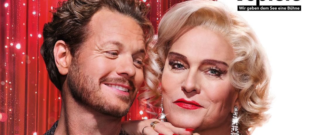 Ein Plakat für das Theaterstück 'Ein Käfig voller Narren' mit Alfons Haider und Mark Seibert vor rotem Vorhang.