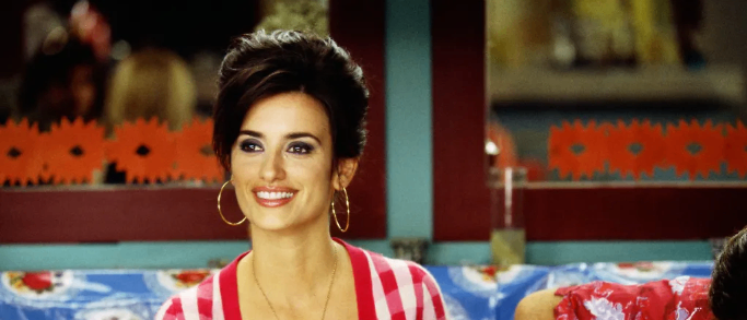 Eine Frau in einem rot-weiß gestreiften Pullover lächelt und klatscht, während ein Mann Gitarre spielt.