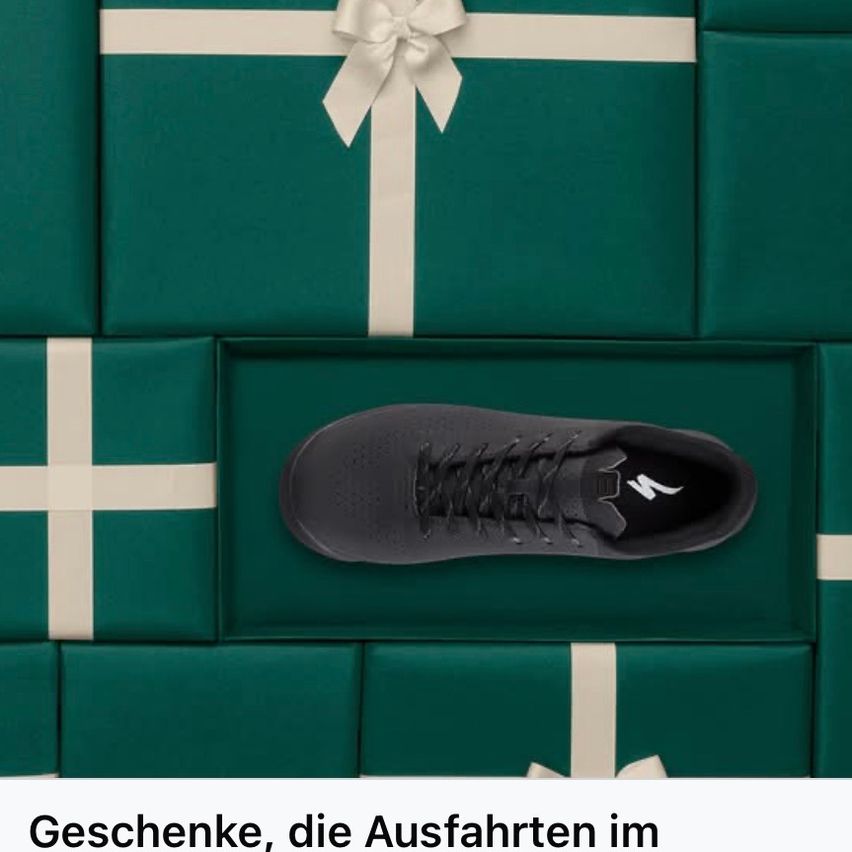 Ein schwarzer Schuh befindet sich in der Mitte eines Stapels grüner Geschenkboxen. Das Bild hat einen weißen Rand und der Text darunter lautet 'Geschenke, die Auffahrten im.'