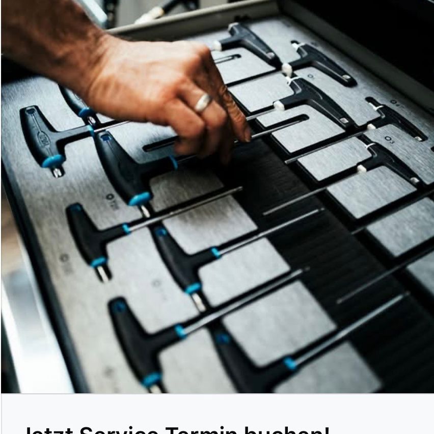 Eine Person handhabt einen Satz Werkzeuge in einer Aufbewahrungsbox. Die Werkzeuge sind schwarz und blau mit einem silbernen Ring. Die Person trägt einen Ring am Finger.