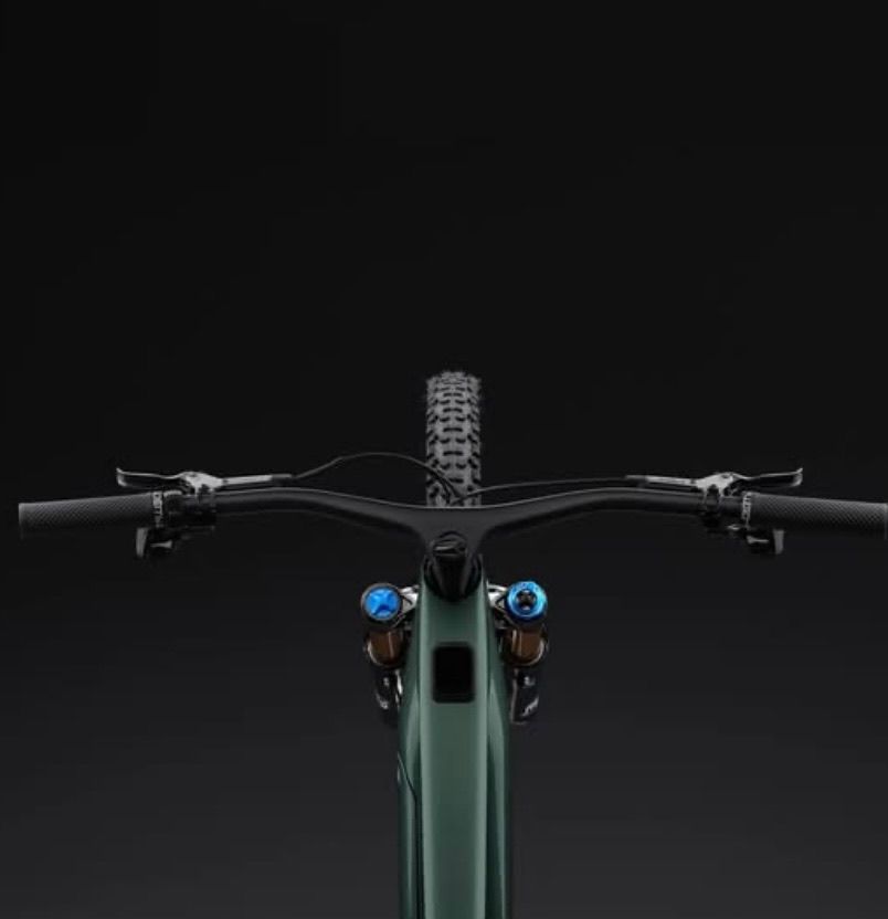A close-up view of a green bicycle's front with a black handlebar, blue lights, and a black tire on a dark background.