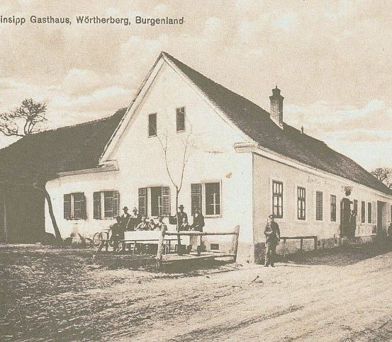 Ein altes Foto zeigt eine Gruppe von Menschen, die vor einem Gebäude stehen und sitzen. Der Ort ist mit Peinsipp Gasthaus, Wrtherberg, Burgenland beschriftet.