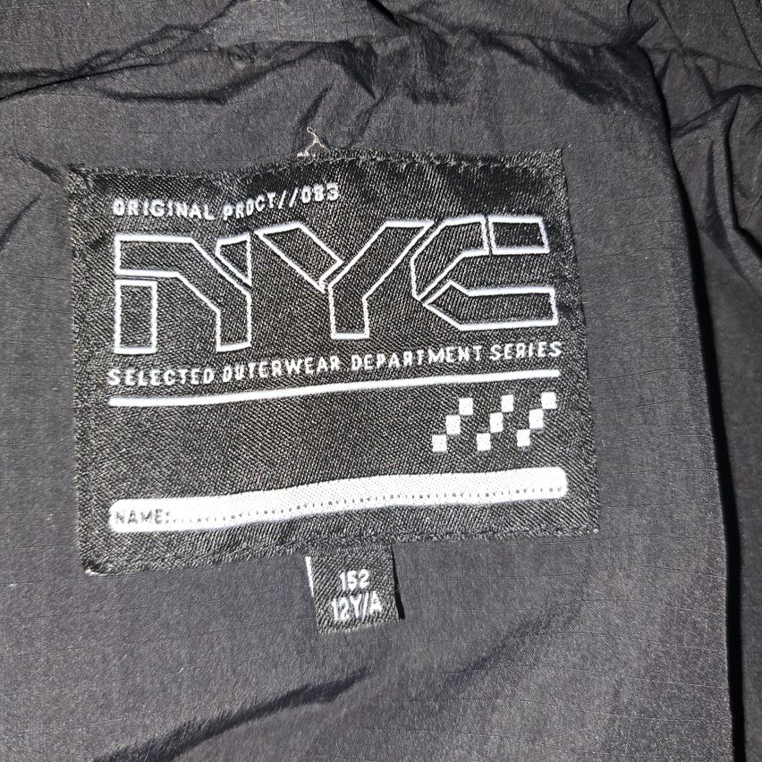 Black jacket label for NYC Selected Outerwear Department Series. White text on a gray background. Label includes 'Original Product', 'NYC', 'Selected Outerwear Department Series', and a barcode.