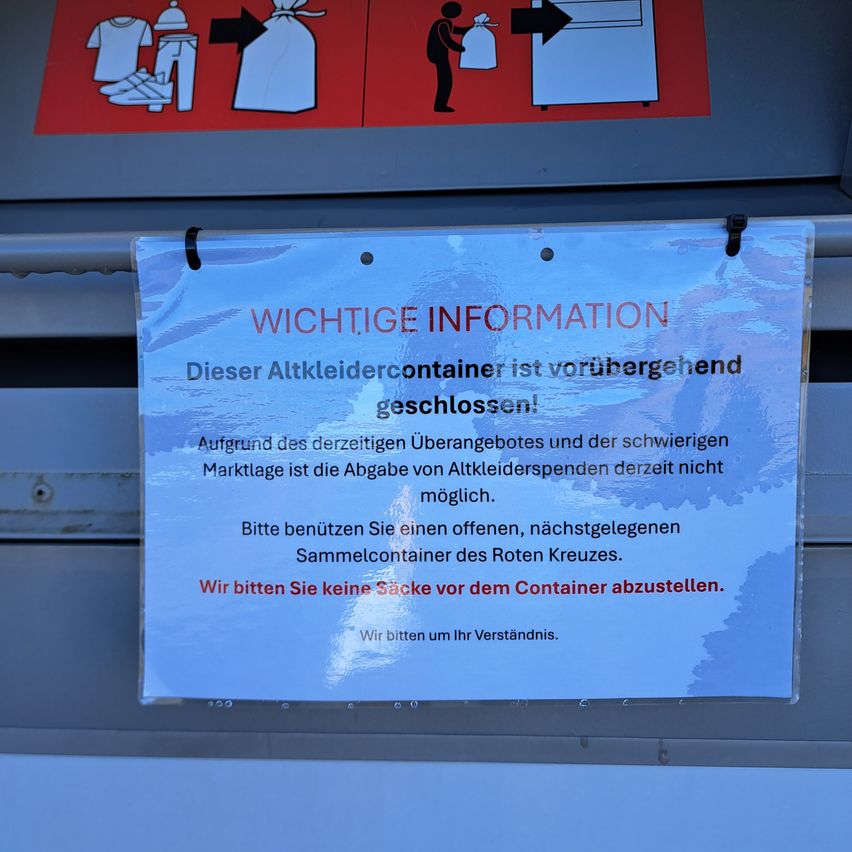 A notice is posted on a closed container for old clothes. It says, 'Important Information: This container for old clothes is temporarily closed. Due to the current lockdown and difficult market conditions, the collection of old clothes is not possible at this time. Please use an open, nearby collection container of the Red Cross. We ask you not to place bags in front of the container. We ask for your understanding.'