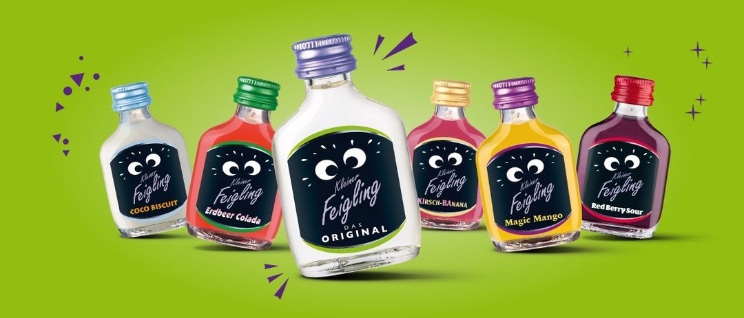 Fünf kleine Flaschen mit farbiger Flüssigkeit. Jede Flasche hat einen anderen Geschmack. Eine Flasche ist klar und die anderen haben farbige Kappen. Sie sind auf einem grünen Hintergrund dargestellt.