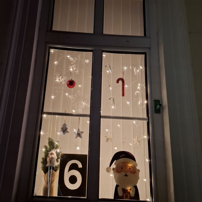 Ein Fensterdisplay für den sechsten Weihnachtstag mit dem Weihnachtsmann und Weihnachtslichtern in Form von Schneeflocken und Zuckerstangen.