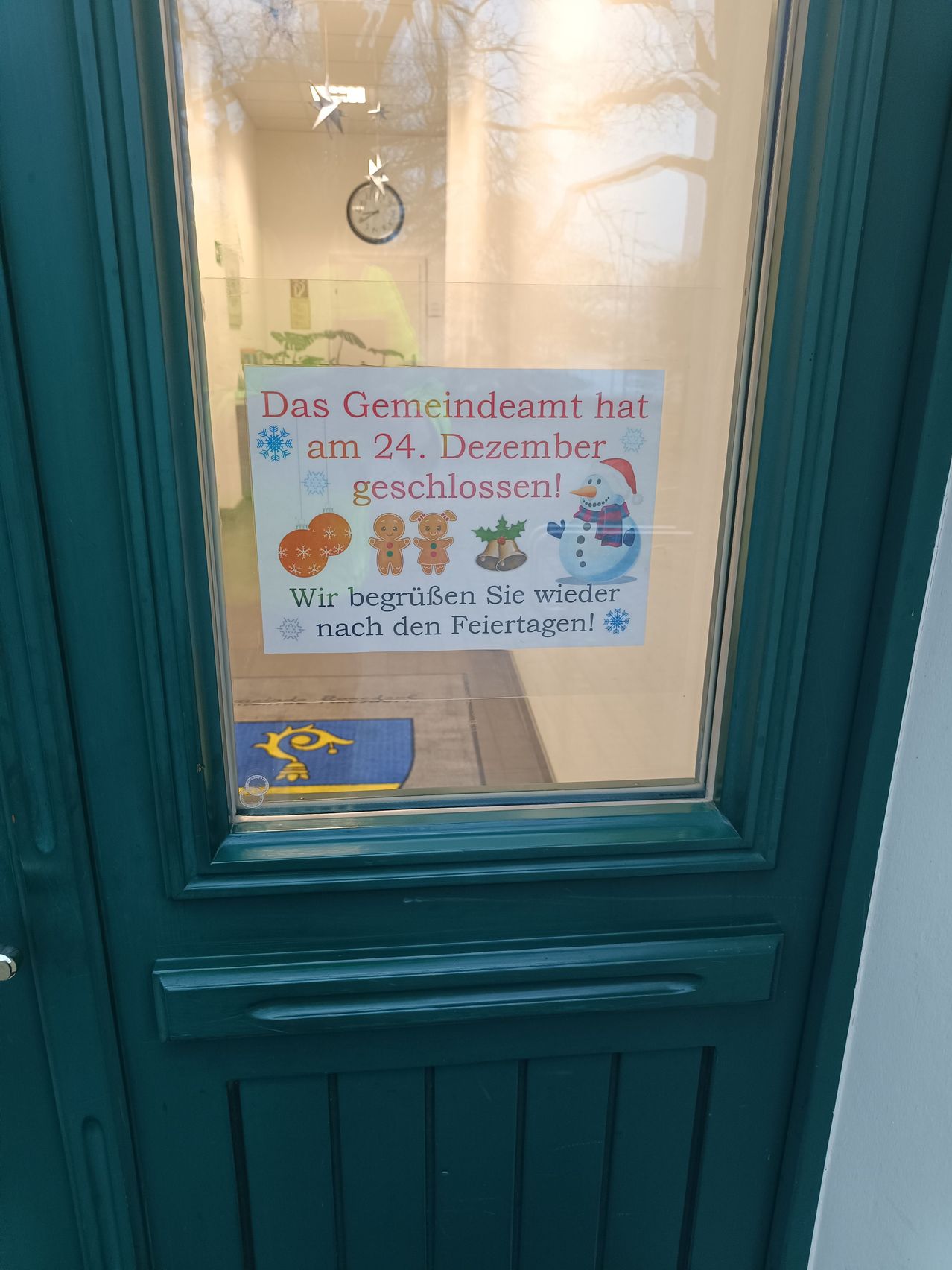 Eine grüne Tür mit einem Schild, das anzeigt, dass das Gemeindeamt am 24. Dezember geschlossen ist. Das Schild teilt mit, dass sie nach den Feiertagen wieder öffnen.