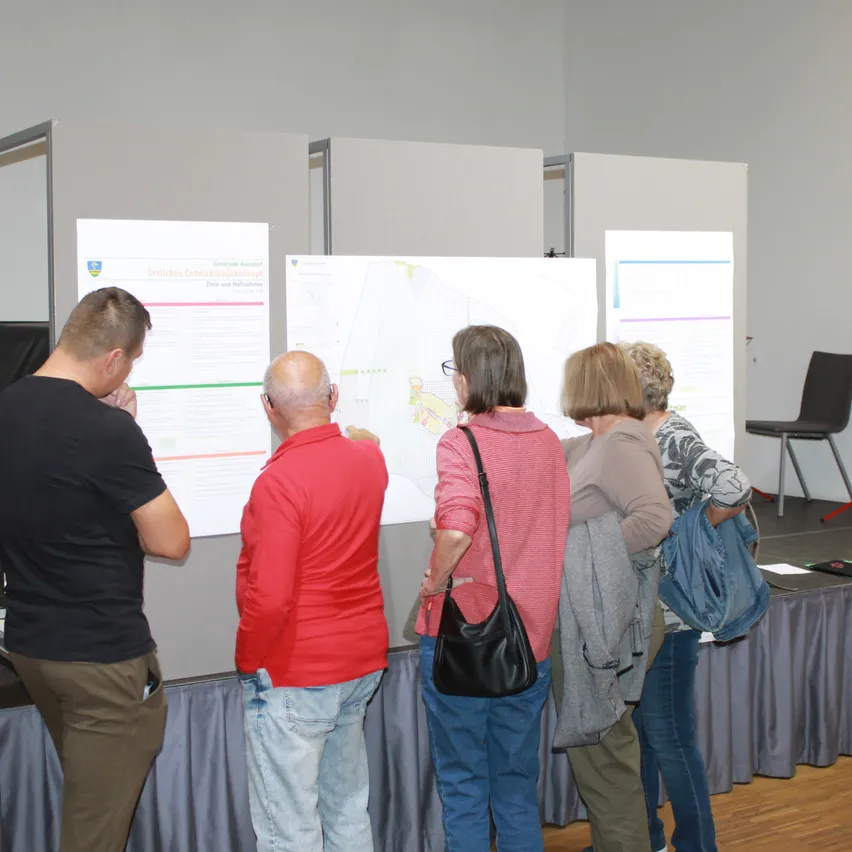 Diskussion über Gemeindeentwicklung: Bürger informieren sich über Pläne in einer Ausstellung.