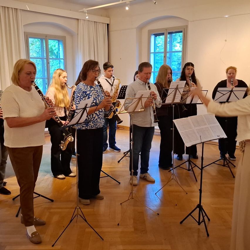 Eine Gruppe von Menschen steht in einem Raum und hält Musikinstrumente. Sie sind wahrscheinlich eine Band. Sie bereiten sich wahrscheinlich auf eine Aufführung vor.