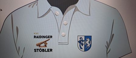 Ein hellblaues Polohemd mit weißen Knöpfen. Links befindet sich ein Logo mit dem Wort Raidinger und einem Bild eines hölzernen Hammers. Rechts ist ein blaues und weißes Schild mit einem Einhorn und Trauben.