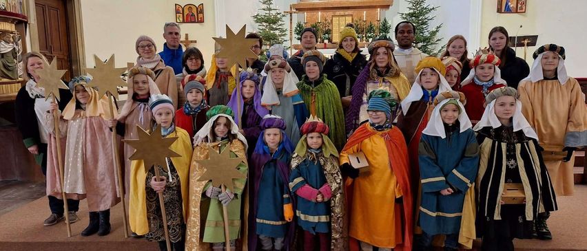 Eine Gruppe von Kindern in traditionellen Kostümen, möglicherweise für ein Weihnachtsspiel, posiert für ein Foto in einer Kirche.