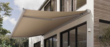 Zwei Ansichten eines modernen Hauses mit einem Terrassenbereich. Die Terrasse hat ein großes Vordach, eine Couch und einen Tisch mit einer Tasse und einer Schüssel. Es gibt Bäume und einen Berg im Hintergrund.