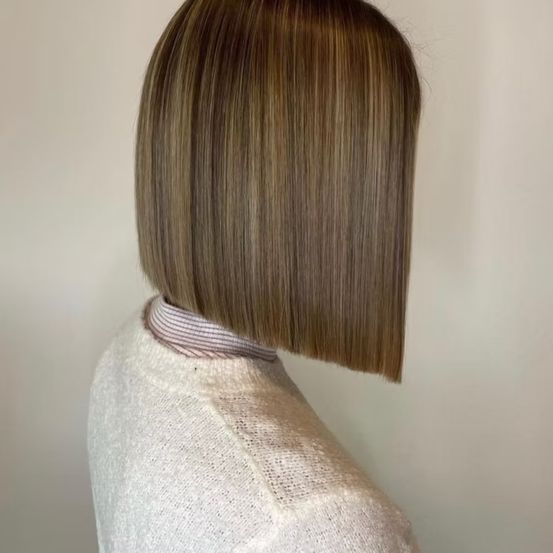 Ein Blick von hinten auf eine Frau mit braunem Haar, gestylt in einem Bob-Cut, und einem hellen Pullover. Das Haar hat Highlights und ist leicht geschichtet.