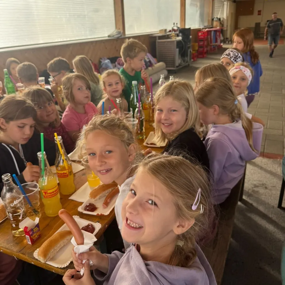 Eine Gruppe von Kindern sitzt an einem Tisch in einer Cafeteria und genießt ihre Mahlzeiten.