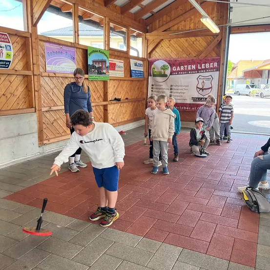 Eine Gruppe von Kindern spielt Ringwurf in einem Holzschuppen.