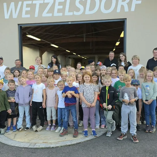 Eine Gruppe von Kindern und Erwachsenen steht vor einem Gebäude mit der Aufschrift 'ESV Wetzelsdorf'.