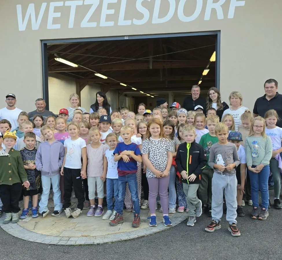Eine Gruppe von Kindern und Erwachsenen steht vor einem Gebäude mit der Aufschrift 'ESV Wetzelsdorf'.