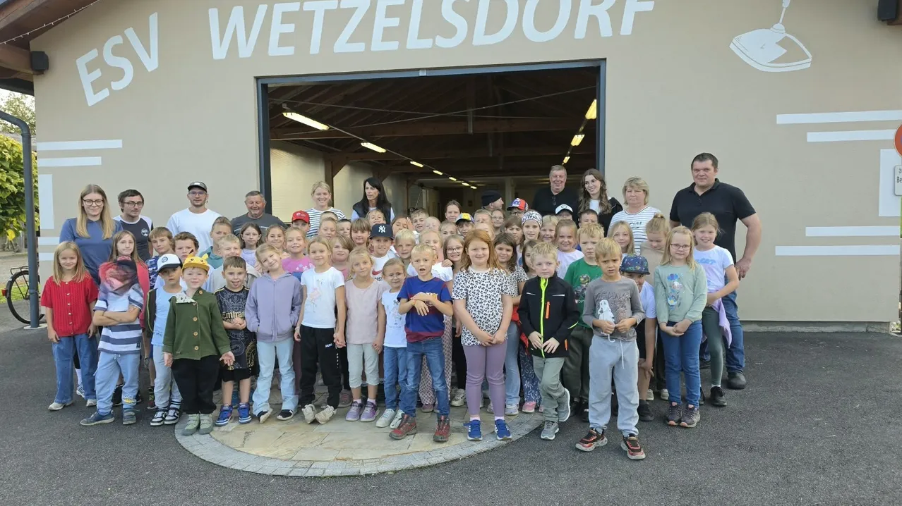 Eine Gruppe von Kindern und Erwachsenen posiert für ein Foto vor einem Gebäude mit den Worten 'ESV Wetzelsdorf'.