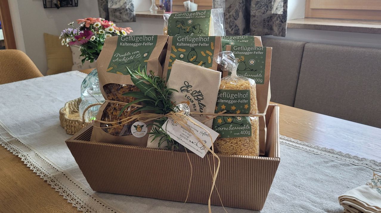 Eine braune Box gefüllt mit verschiedenen Lebensmitteln, einschließlich Nudeln und einem Rosmarinstrauß, alles in umweltfreundlicher Verpackung verpackt.
