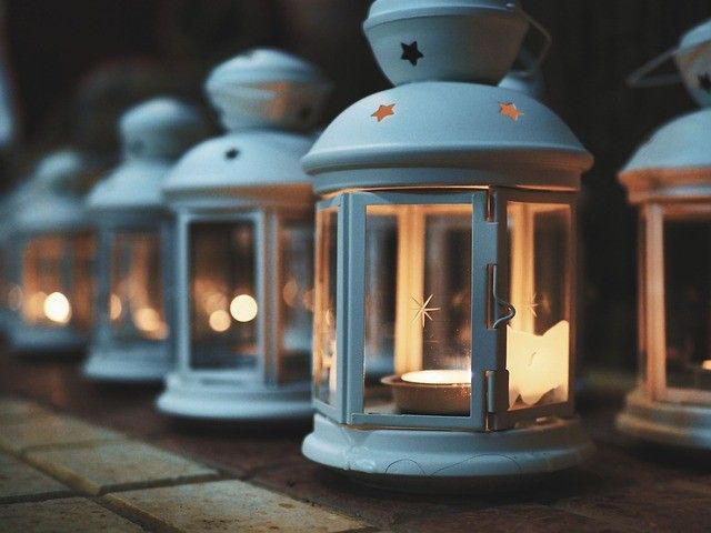Eine Reihe weißer Laternen mit Sternendesigns sind auf einer Ziegeloberfläche beleuchtet. Die Laternen strahlen warmes Licht aus.