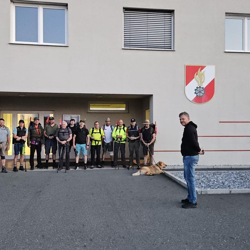 Eine Gruppe von Menschen vor einem Gebäude, möglicherweise einem Club, mit einem Hund und einem Mann in der Nähe.