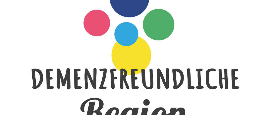 Ein kreisförmiges Logo mit weißem Hintergrund und blauen, roten, grünen und gelben Kreisen. Der Text 'DEMENZFREUNDLICHE REGION' ist in Schwarz unter den Kreisen angezeigt.