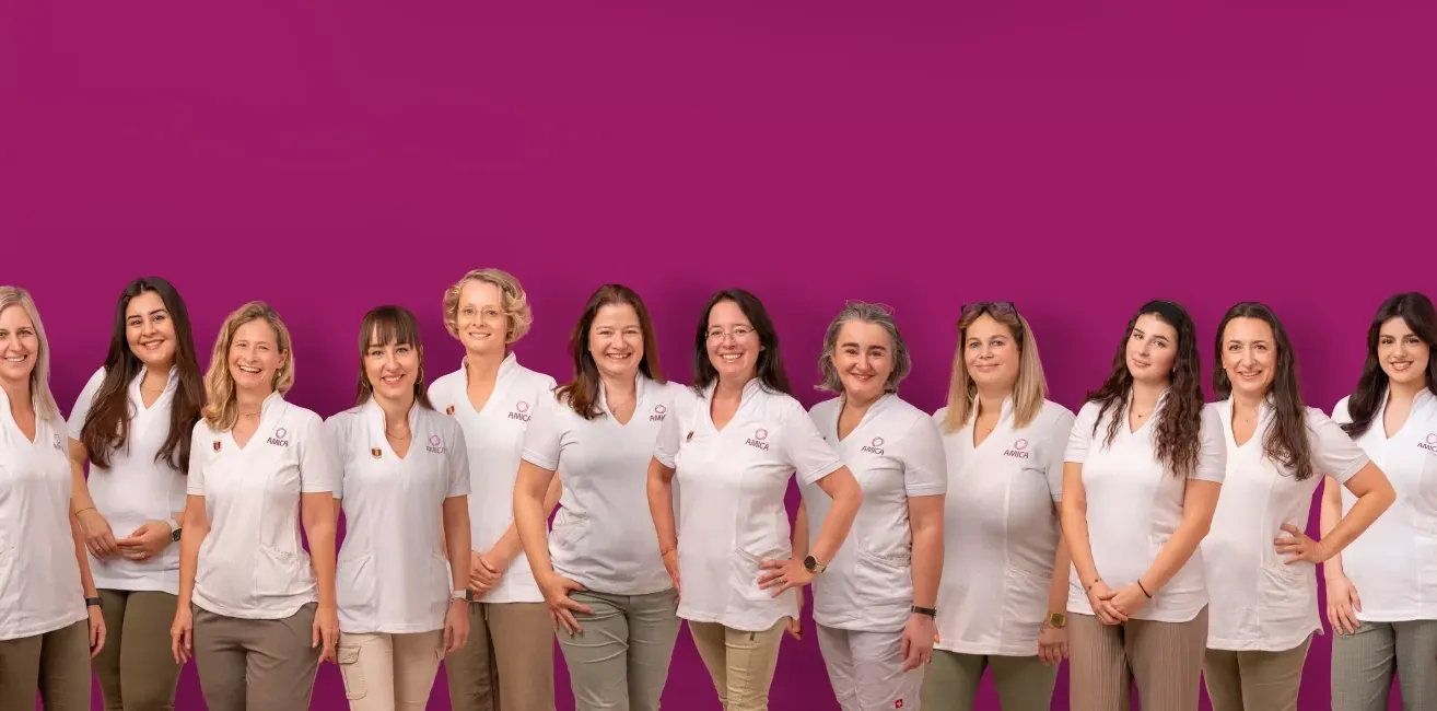 Eine Gruppe von Frauen in weißen Uniformen mit einem Logo auf der Brust posiert für ein Foto vor einem lila Hintergrund.