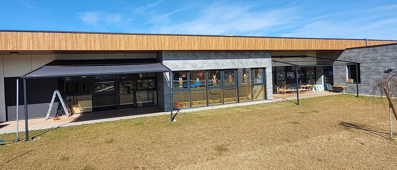Eine Vogelperspektive eines modernen Gebäudes mit Glaswänden und einem braunen Dach, auf einem kahlen Feld unter einem klaren blauen Himmel mit einigen Wolken.