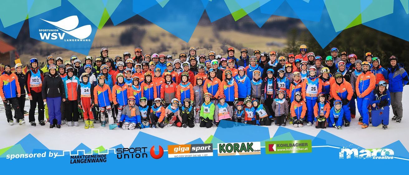 Eine Gruppenaufnahme eines Skiteams in blauen und orangefarbenen Uniformen posiert vor einem verschneiten Berg. Das Team besteht aus Erwachsenen und Kindern, alle tragen Skiausrüstung. Der Hintergrund zeigt ein blaues und weißes Design. Sponsorenlogos sind sichtbar.