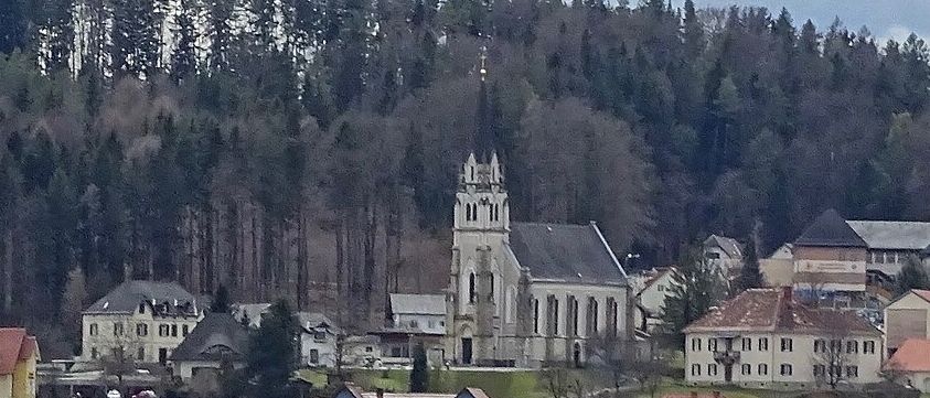 Ein Dorf mit vielen Häusern, umgeben von einem dichten Wald. Die Kirche steht prominent in der Mitte, mit einem Kirchturm.