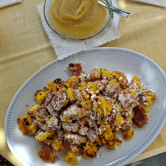 Ein Teller mit gebratenen Kürbisstücken mit einer Schüssel Kürbispüree und einem Löffel auf einem Tisch.