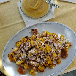 Ein Teller mit gebratenen Kürbisstücken mit einer Schüssel Kürbispüree und einem Löffel auf einem Tisch.