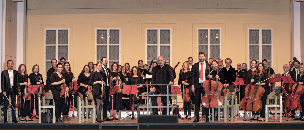 Bild enthält, Indoors, Music, Musical Instrument, Musician, Orchestra, Performer, Person, Handbag, Group Performance, Music Band