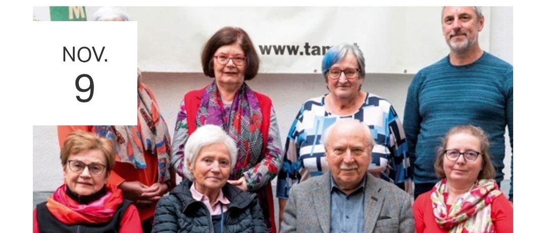Eine Gruppe älterer Menschen posiert für ein Foto. Die Frau in der Mitte trägt ein Stethoskop. Der Mann rechts trägt einen grauen Mantel. Hinter ihnen ist ein weißer Banner mit dem Text www.tar.