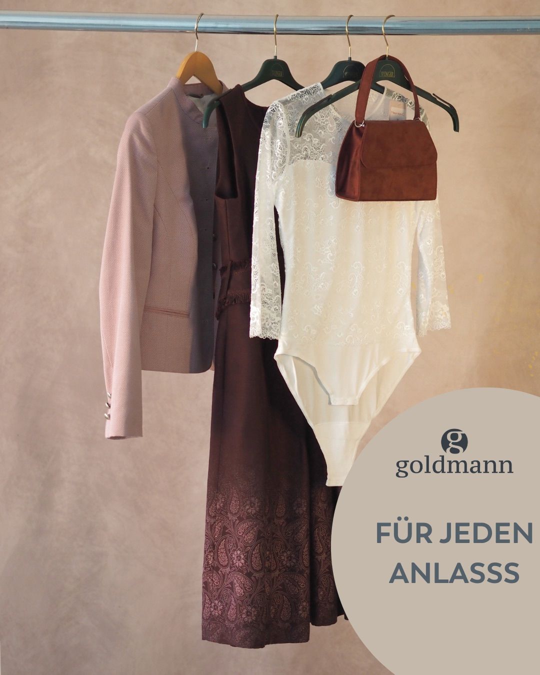 Eine Bekleidungswerbung für Goldmann zeigt eine Jacke, ein Kleid und einen Bodysuit, die an Kleiderbügeln hängen. Der Text lautet 'Für jeden Anlass.'