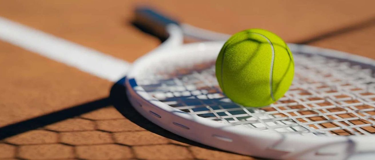 Ein Tennisschläger mit einem Tennisball darauf auf einem Tennisplatz.