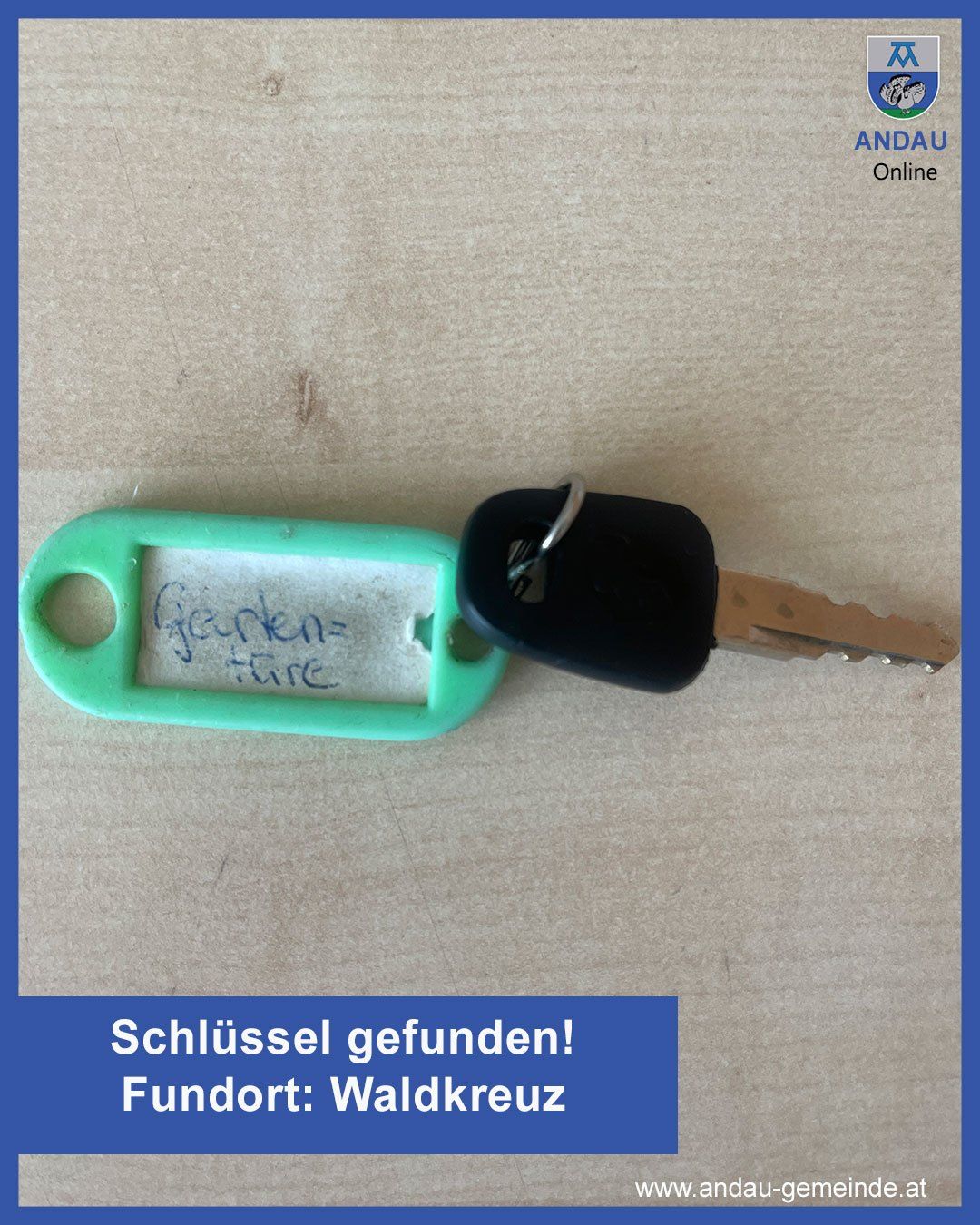 Ein grüner Schlüsselanhänger mit einem Aufkleber, der Geyken=fire liest, auf einem braunen Schlüssel, auf einer hellbeigen Oberfläche mit einem blauen Rand. Das Bild hat einen Wasserzeichen mit dem Text ANDAU Online.