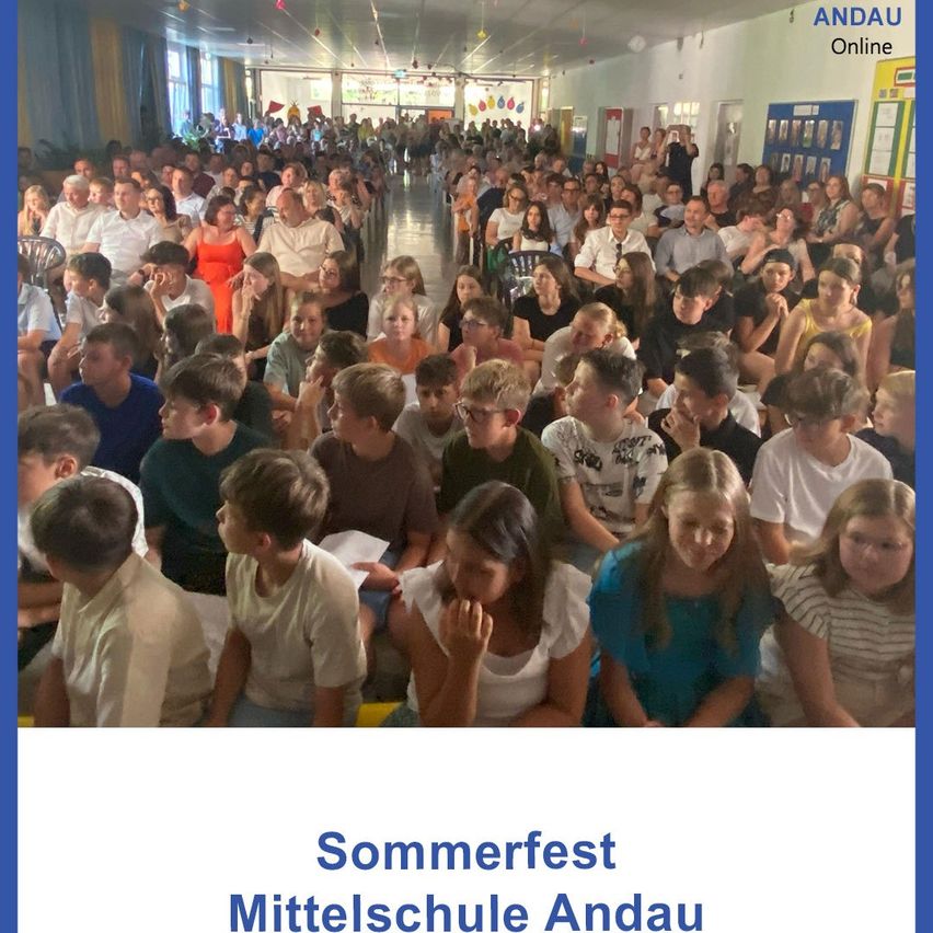 Eine große Menschenmenge sitzt in Reihen, wahrscheinlich bei einem Sommerfest. Das Bild hat einen blauen Rand mit den Worten 'Sommerfest Mittelschule Andau' unten.