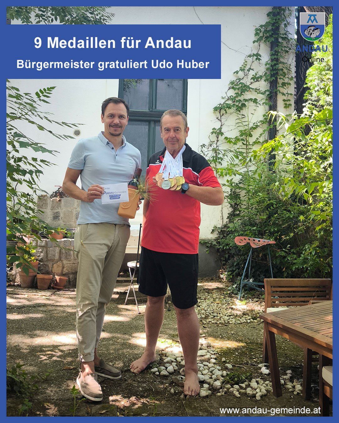 Zwei Männer stehen draußen, einer hält eine Flasche und ein Zertifikat, der andere trägt mehrere Medaillen. Hinter ihnen steht ein Gebäude mit Pflanzen und einem Tisch.