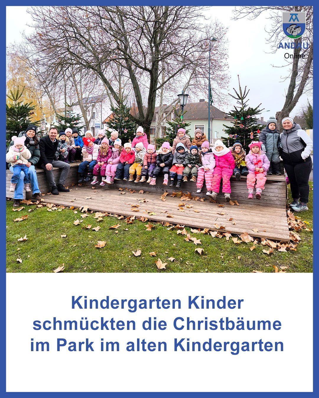 Eine Gruppe von Kindergartenkindern und ihren Eltern schmücken Weihnachtsbäume in einem Park in der Nähe des alten Kindergartens.