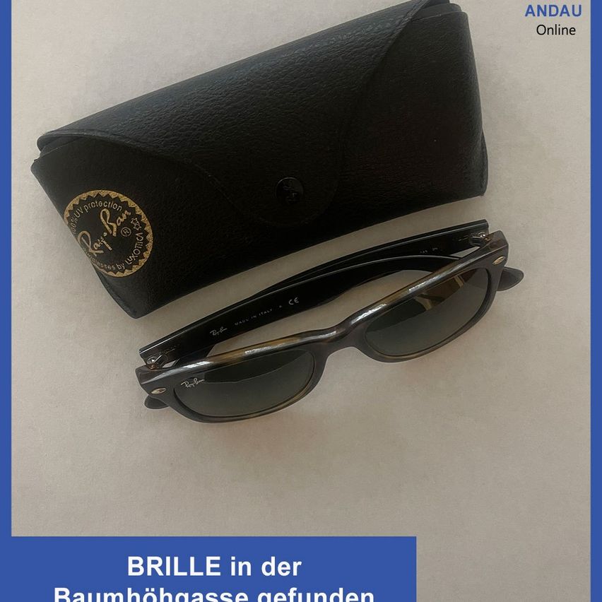 Schwarze Sonnenbrille mit Etui und Logo auf dem Etui auf einer weißen Oberfläche. Der Text lautet Brille in der Baumbogasse gefunden.