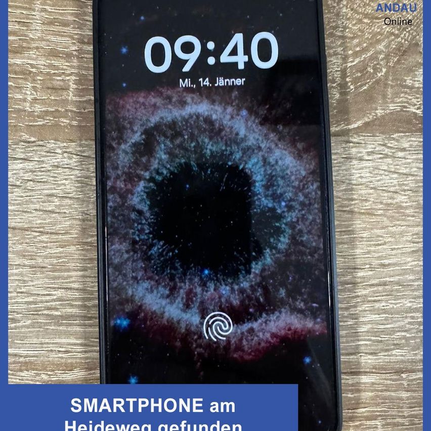 Ein Smartphone mit einem Bildschirm, der die Zeit 09:40, ein Fingerabdrucksymbol und einen galaktischen Hintergrund anzeigt, steht auf einer Holzoberfläche. Der Text 'Smartphone am Heideweg gefunden' ist auf einem blauen Hintergrund geschrieben.